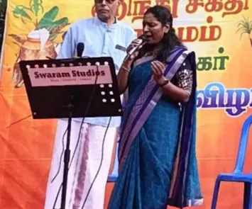 Woman singing on stage at temple cultural event with microphone