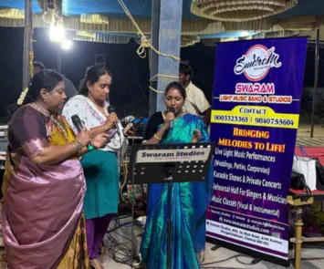 Women singing at temple event with Swaram Studios banner