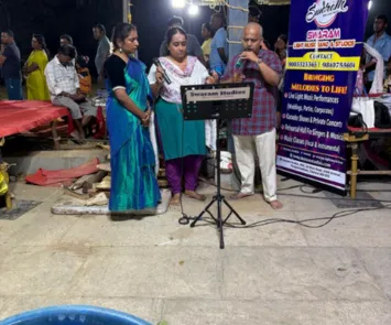 Group singing performance at outdoor temple event with mic setup