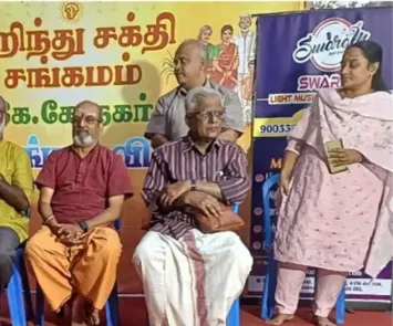 Guests seated on stage at temple cultural event with banner