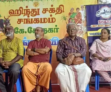 Guests seated on stage at temple cultural program with banner