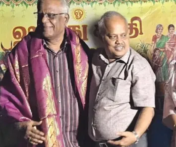 Man receiving shawl honor at cultural event with guests