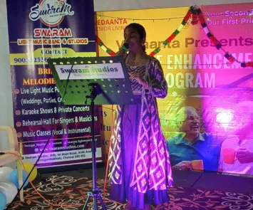 Female singer performing on stage with Swaram Studios banner