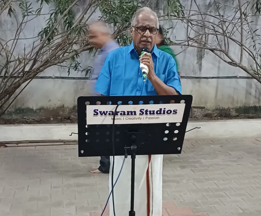 Man speaking with microphone at outdoor event with music stand