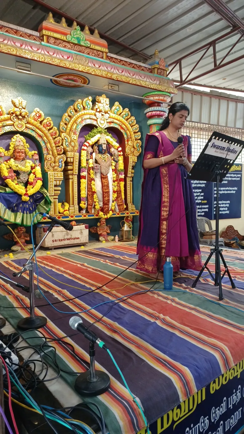 Woman singing at temple stage with decorated idols
