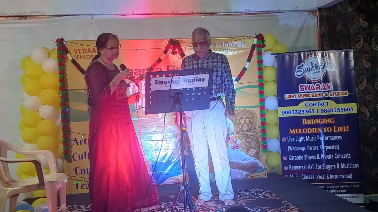 Man and woman singing on stage at music event with banner