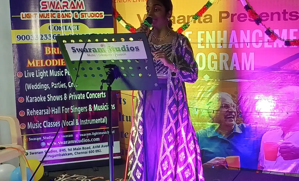 Woman singing on stage at music event with Swaram Studios banner