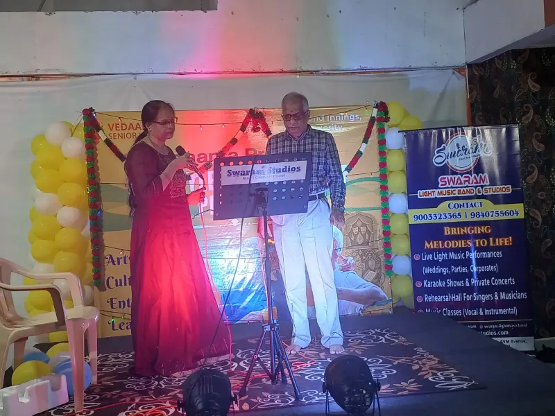 Man and woman singing on stage at music event with banner