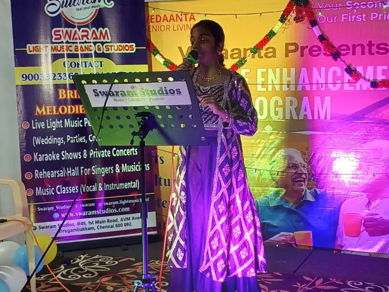 Woman singing on stage at music event with Swaram Studios banner